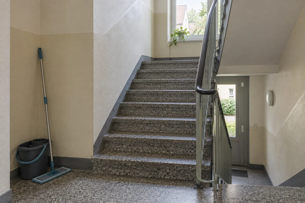 Treppenhaus mit Steinboden und Reinigungsgerät.